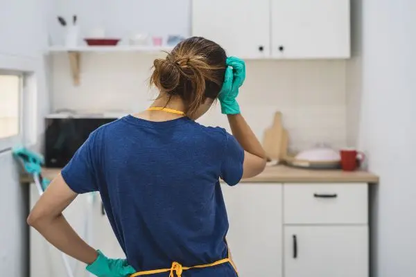 Woman in the kitchen wearing cleaning gloves frustrated of the mess rodents left